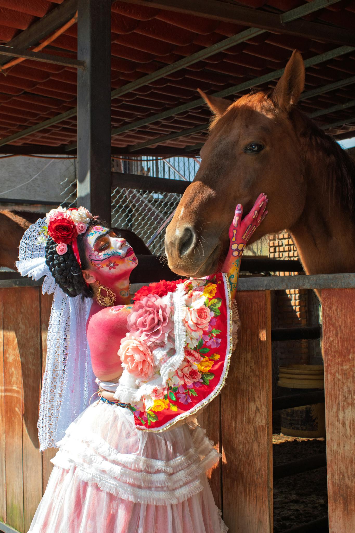 A woman in Day of the Dead makeup interacts with a horse in Villa Milpa Alta, Mexico.