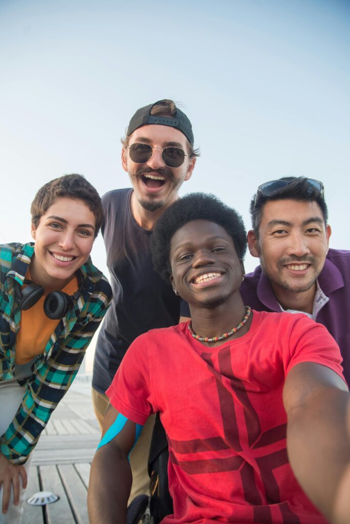 Diverse group of friends smiling and posing together outdoors under a clear sky.
